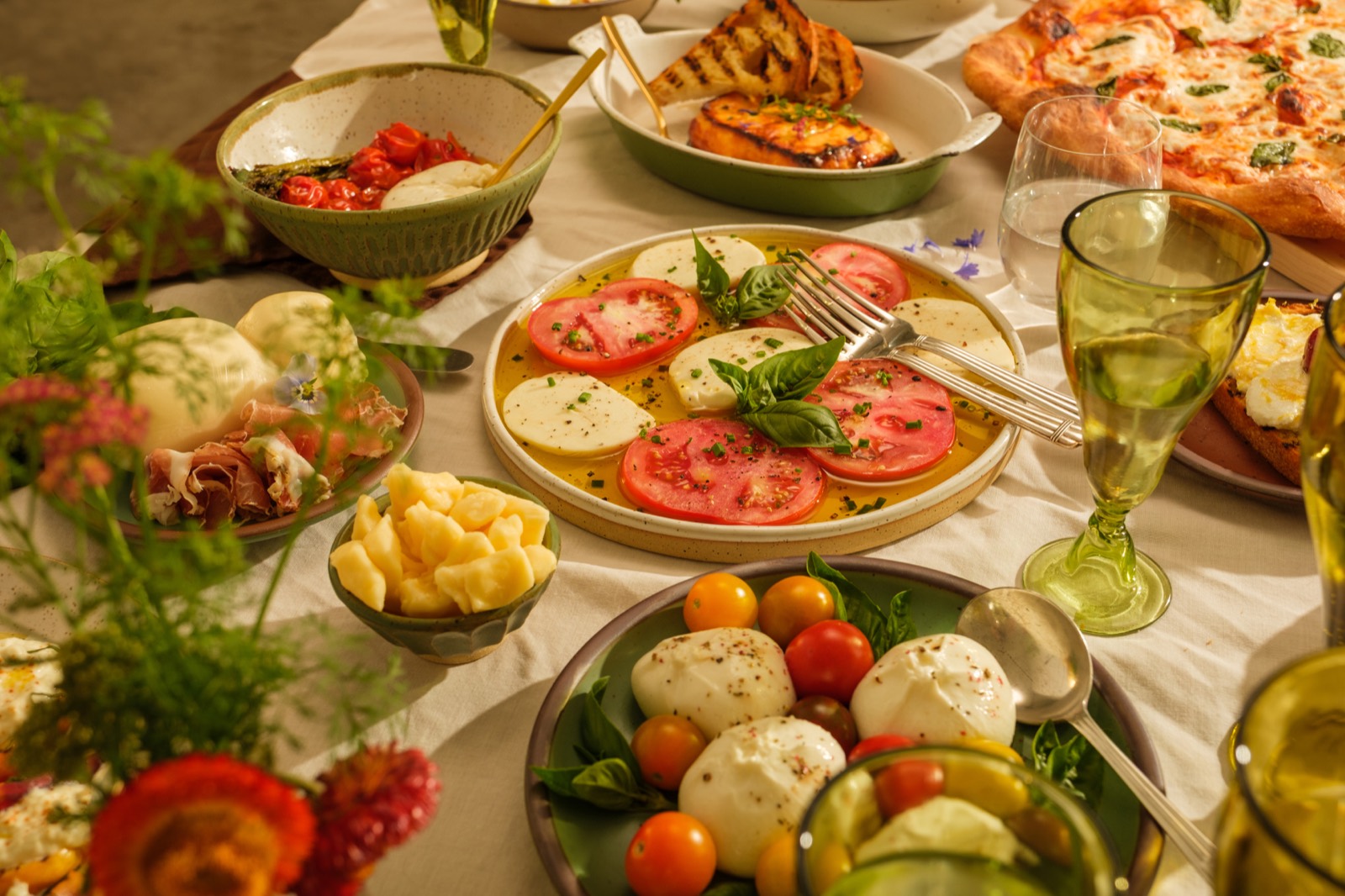 A table set with caprese, burrata, and fresh mozzarella