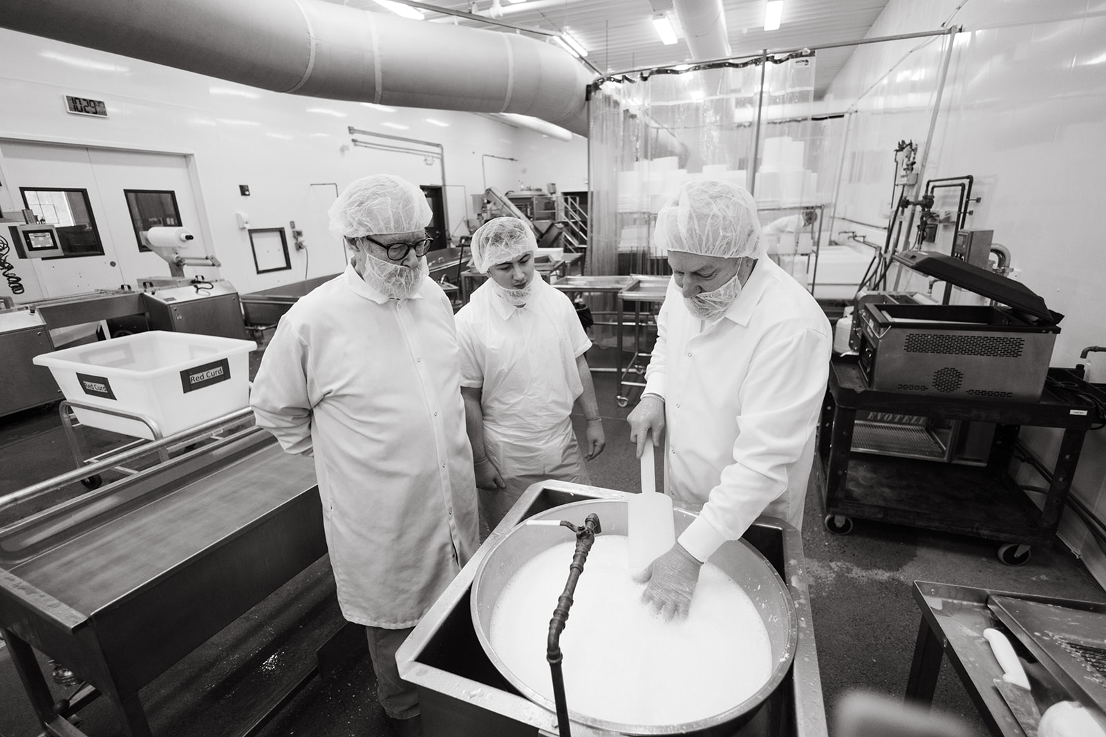 Cheesemakers working a vat of curd in the North Bennington creamery